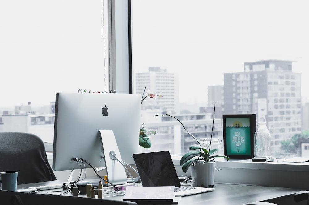 An Apple PC and laptop overlooking an office to demonstrate how to set business goals and objectives