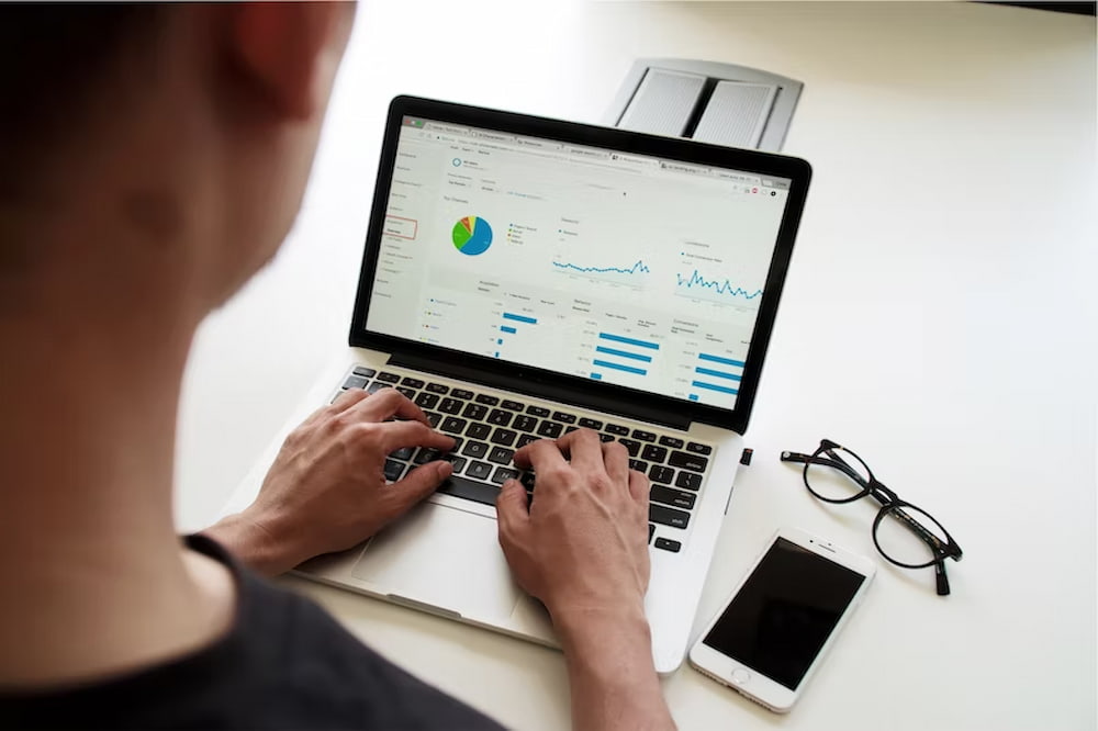 man sat at laptop typing in figures for business growth