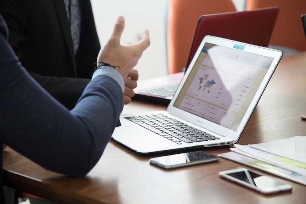 An image of a man on a computer talking to someone next to hi